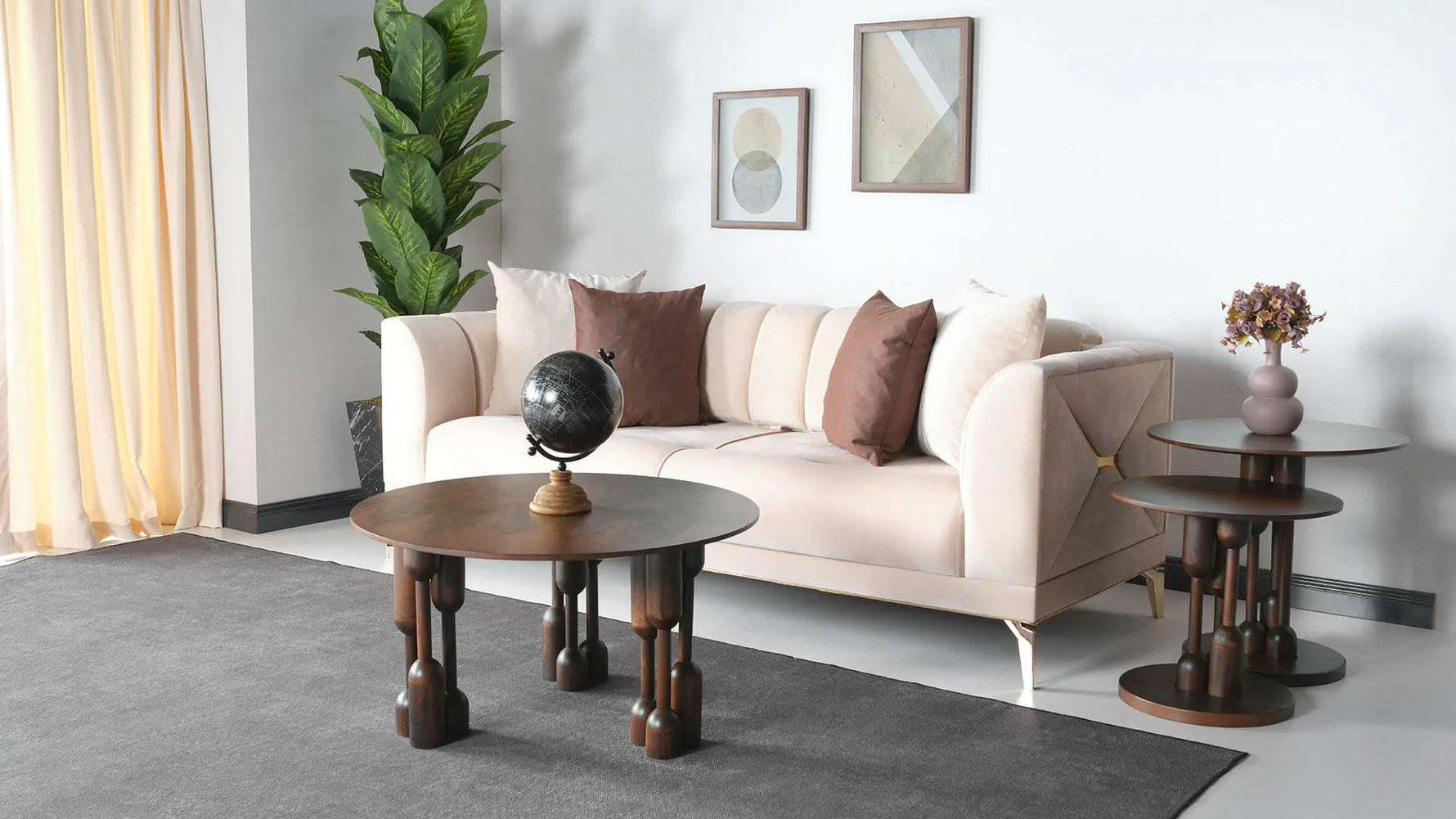 A stylish round coffee table with a dark wood finish and distinctive designed legs, placed on a grey carpet in a room with a beige sofa and a potted plant in the background.