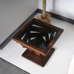 Modern end table with a twisted geometric wood base and a sleek tempered glass top.
